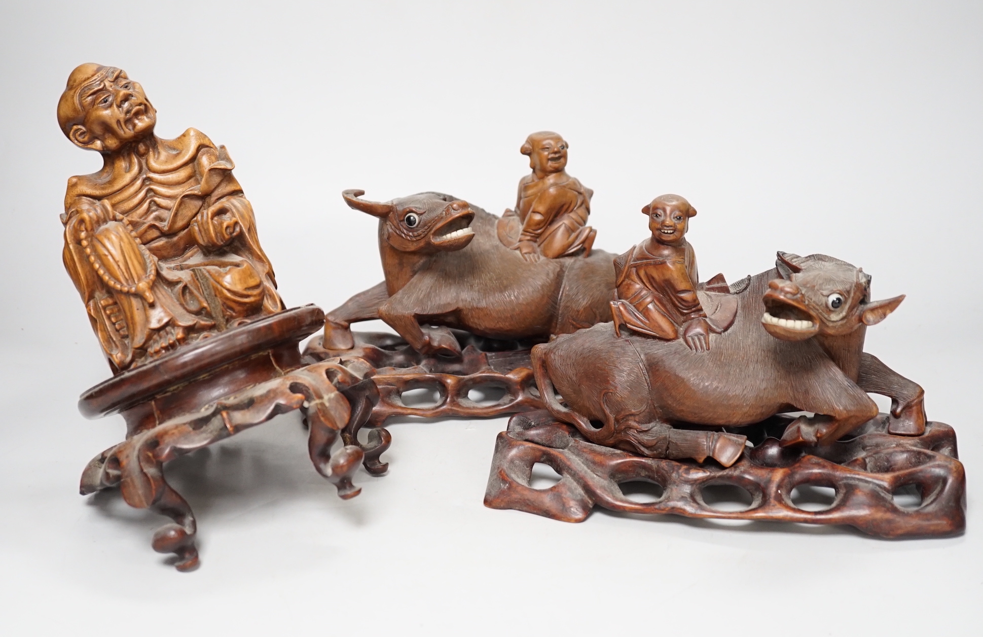 A pair of Chinese carved hardwood buffalo carvings, and a similar figure of a luohan, latter 24cm - damaged